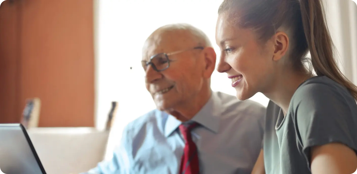 Elderly Man Looking at Laptop With Carer [header]